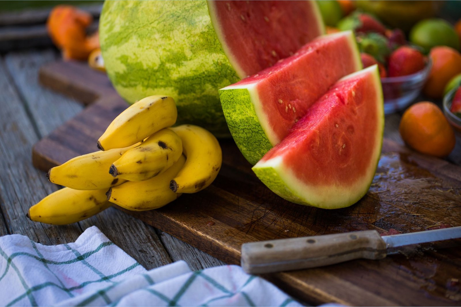 Kaliumreiche Bananen leien op engem Schneidebrett nieft enger L-Citrullin-räich, geschniddener Waassermeloun