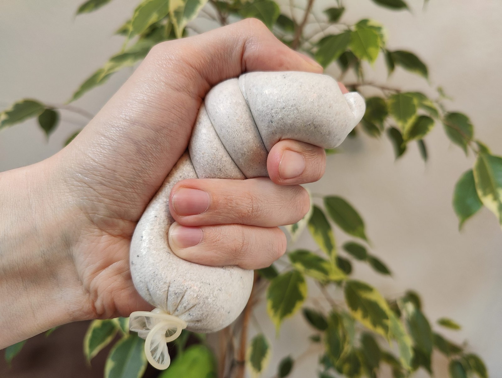 En ofgelafte Kondom gefëllt mat Sand an der Hand vun engem deen et als Stressball benotzt